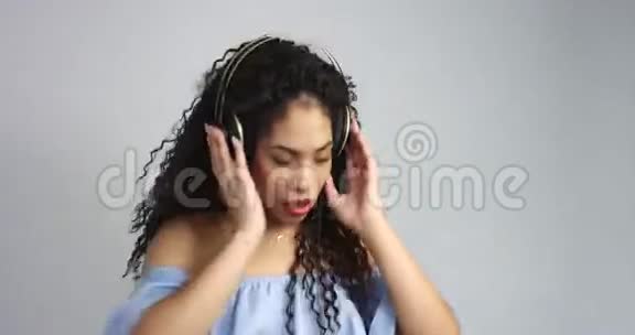 带着卷发的混血女人听着耳机里的音乐跳舞视频的预览图