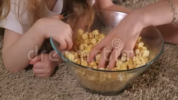 充满爱意的家庭母亲和女儿的女儿正在房间的地板上吃爆米花电视前面视频的预览图