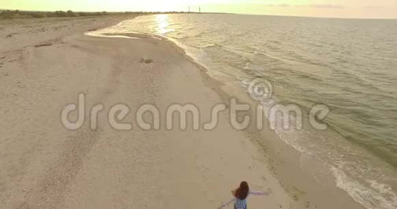 4k空中美丽的女孩在日落时在沙滩上转身视频的预览图