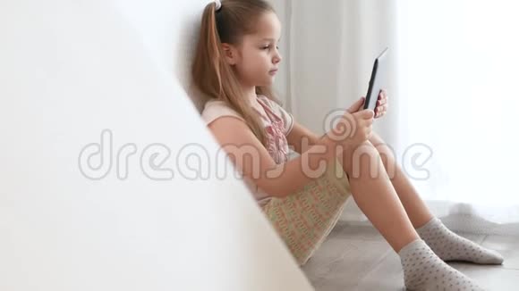 小女孩拿着电脑平板电脑坐在房间的地板上视频的预览图