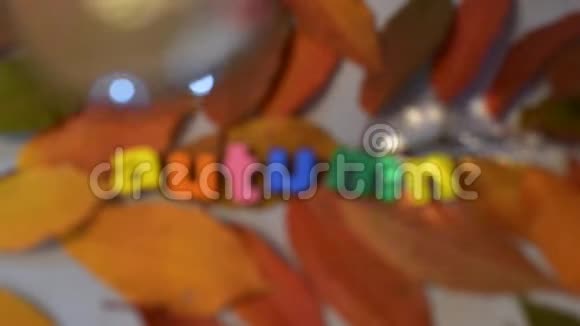 词秋的彩色字母通过放大镜在黄叶背景上视频的预览图