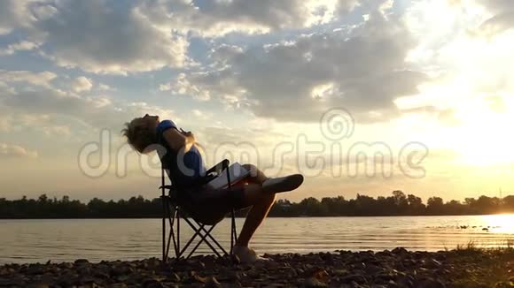 年轻人坐着读着在邋遢的日落时分在河岸上做运动视频的预览图