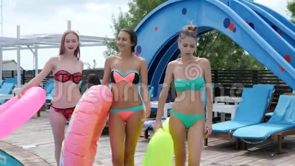 比基尼女郎穿着粉色橡胶圈在池边的木墩上散步女朋友穿着泳衣游泳视频的预览图
