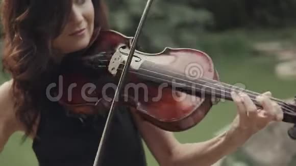 穿裙子的优雅女孩在户外拉小提琴森林中优雅的小提琴手视频的预览图