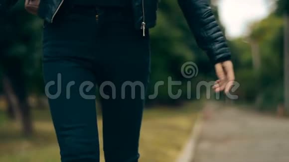 穿着黑色牛仔裤和皮夹克的女孩走在边境上视频的预览图
