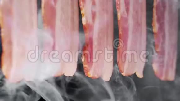 在黑色背景的烟雾中熏出多汁和美味的培根片煮肉猪肉肉视频的预览图