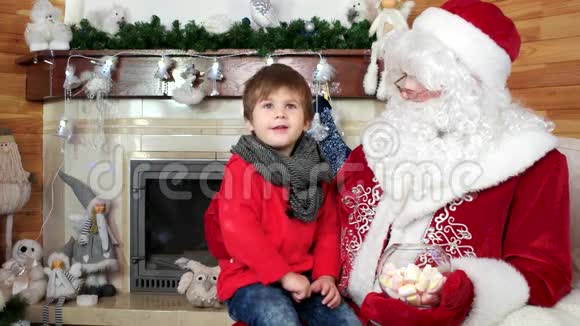 圣诞老人腿上的小男孩告诉圣尼古拉斯他的圣诞祝福节日气氛视频的预览图