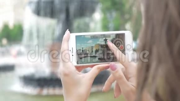 女孩在电话里拍了一张美丽的城市喷泉的照片视频的预览图