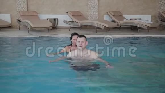 年轻的男人和女人在游泳池里开玩笑和微笑视频的预览图