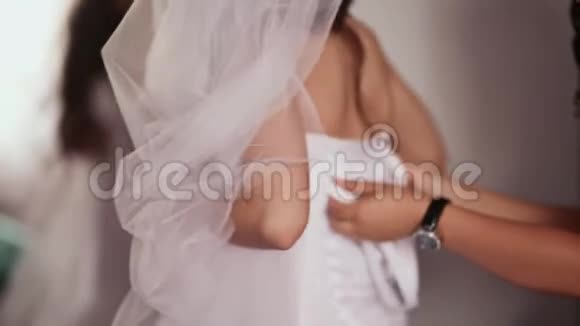 新娘的晨训女朋友帮新娘系上婚纱的紧身衣视频的预览图