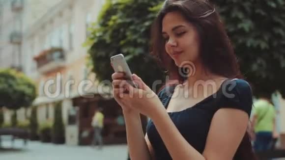 一位美丽的长发女子站在城市里用手机发短信近距离观看视频的预览图