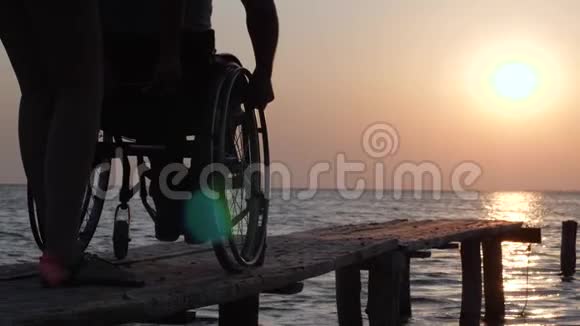 在日落时分在轮椅上帮助人们对抗水和天空视频的预览图