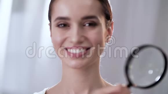 女人透过放大镜和微笑靠近视频的预览图