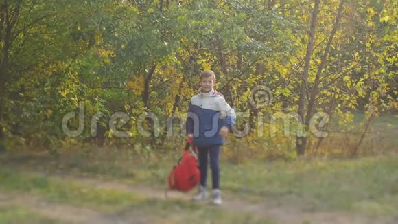 那个动作慢的男孩背着背包转过身在公园里的秋天愉快地娱乐慢动作视频的预览图