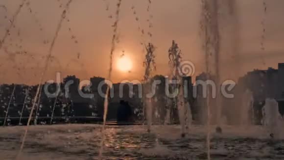一对相爱的夫妇坐在喷泉旁看着美丽的日落视频的预览图