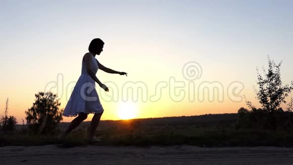 快乐的女人在空中跳跃在斯隆莫的美好日落中抚摸她的脚跟视频的预览图