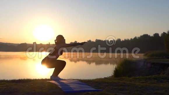 日落时分年轻女子坐在湖边视频的预览图