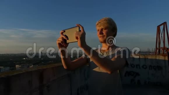 金发男人从屋顶上射出灿烂的日落视频的预览图