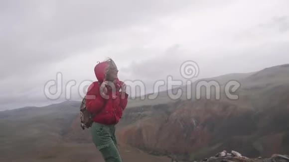 年轻的女游客在大雨下在山上散步一个背着背包的女孩旅行者视频的预览图