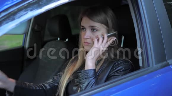 年轻迷人的女人坐在停车的车里用电话发誓视频的预览图