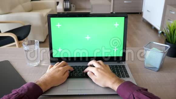 男性手在笔记本电脑键盘上打字用彩色绿色屏幕模拟视频的预览图