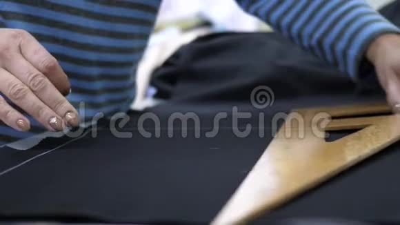 时尚设计员工用白色粉笔在车间的桌子上画黑色组织视频的预览图