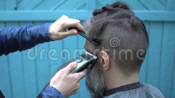 女理发师用电动剃须刀和梳子为留胡子的帅哥理发视频的预览图
