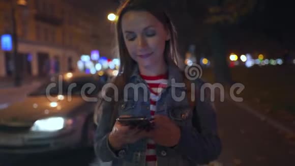 女人一边用智能手机走在城市的街道上视频的预览图