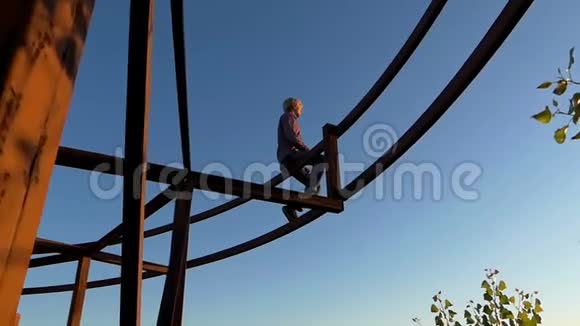 梦一般的人坐在夕阳下的金属建筑上视频的预览图
