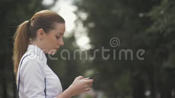 侧视公园内一个大学女生短信手机特写视频的预览图