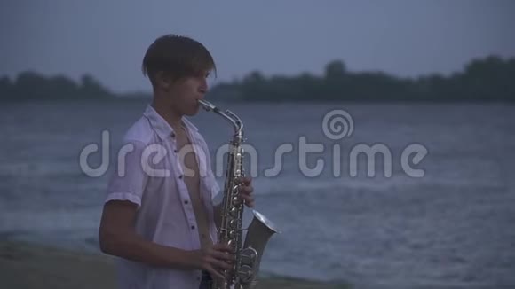 英俊的年轻人正在河岸上吹萨克斯管视频的预览图