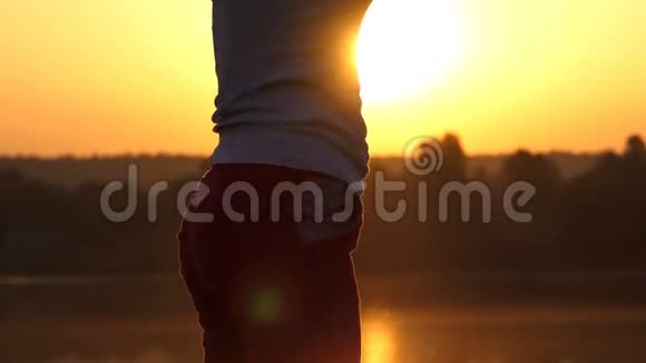 忧郁的女人在夕阳西下的湖岸上弯下腰视频的预览图