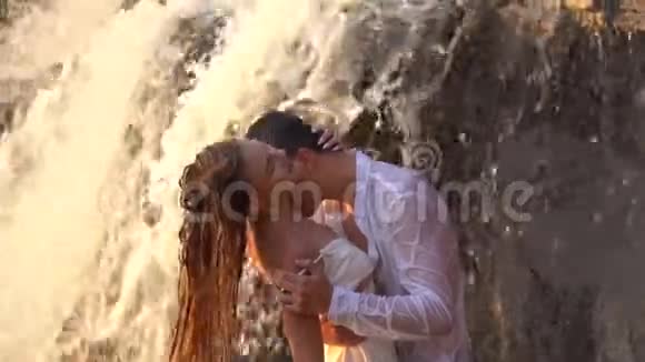 日落时分一个男人亲吻站在瀑布下脖子上的女孩视频的预览图