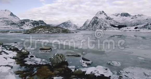 挪威美丽的冬季景观阳光明媚湖面结冰群山环绕视频的预览图