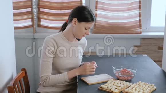 女人用肉馅包饺子看着镜头微笑视频的预览图
