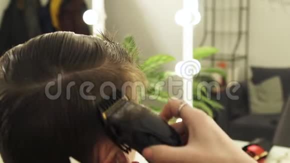 女理发师理发男子头发与电动剃须刀关闭为男性使用电动剃须刀的专业理发师视频的预览图