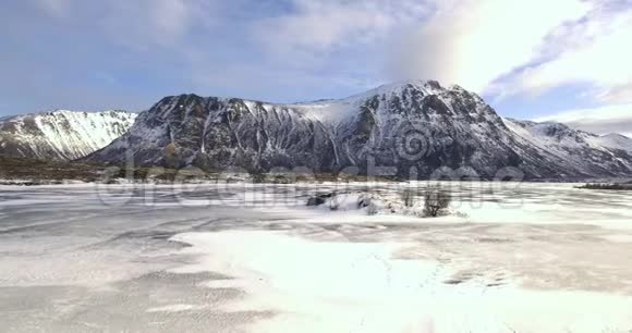 挪威美丽的冬季景观阳光明媚湖面结冰群山环绕视频的预览图