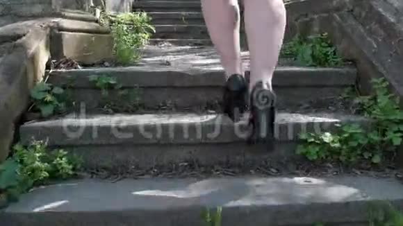 一个穿着黑色高跟鞋和短裙的女人正在攀登古老的楼梯视频的预览图