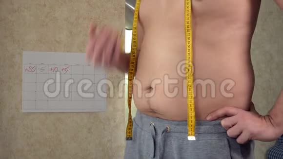 一个胖子测量他的腰一个大啤酒肚健康的生活方式吃苹果视频的预览图