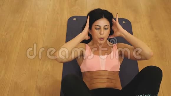 运动服的年轻女子在健身房锻炼腹肌有吸引力的女运动员从事腹部运动视频的预览图