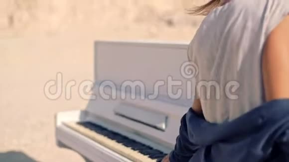 美丽而梦幻的年轻女子在一片荒凉的山脉和一架白色钢琴的背景上超现实主义幻影视频的预览图