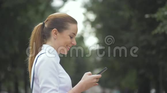 侧视公园内一个大学女生短信手机特写视频的预览图