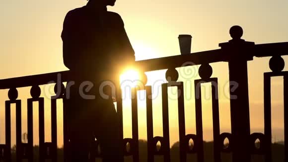 男人从纸杯喝咖啡在斯隆莫的桥上享受日落视频的预览图