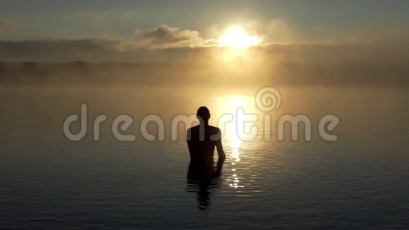 夕阳西下一个年轻人在湖里展示了一个爱的标志视频的预览图