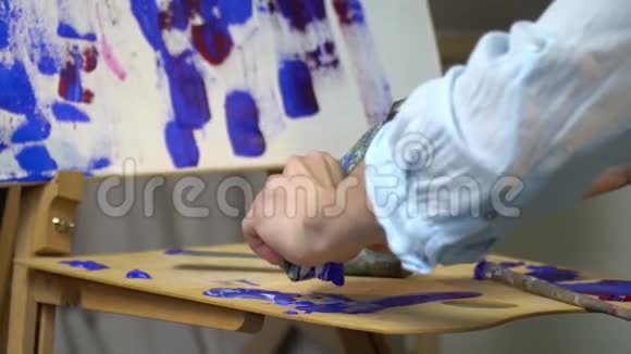 女性的手从木架上挤出蓝色油漆的残留视频的预览图