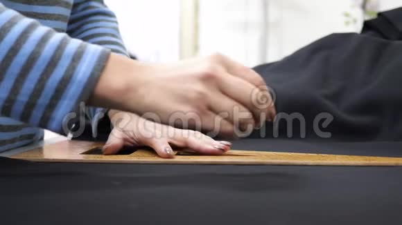 时尚设计女裁缝用白色粉笔在工作场所用黑布画画视频的预览图