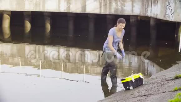 女性生态学家测量城市河流中水的pH视频的预览图