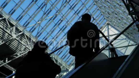 人们在商务中心的自动扶梯上剪影有大窗户视频的预览图