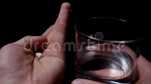 吃药手里拿着清水的药丸和杯子黑色背景视频的预览图