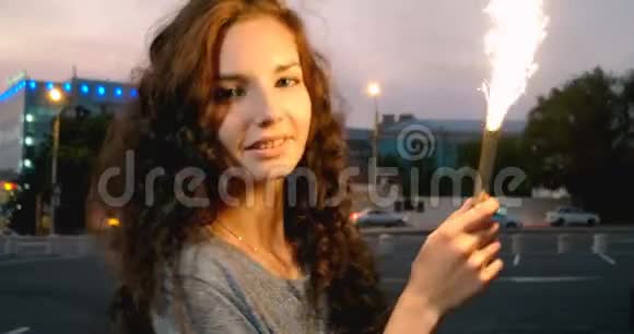 黄昏时分一位年轻女子在街上燃放烟花起舞视频的预览图